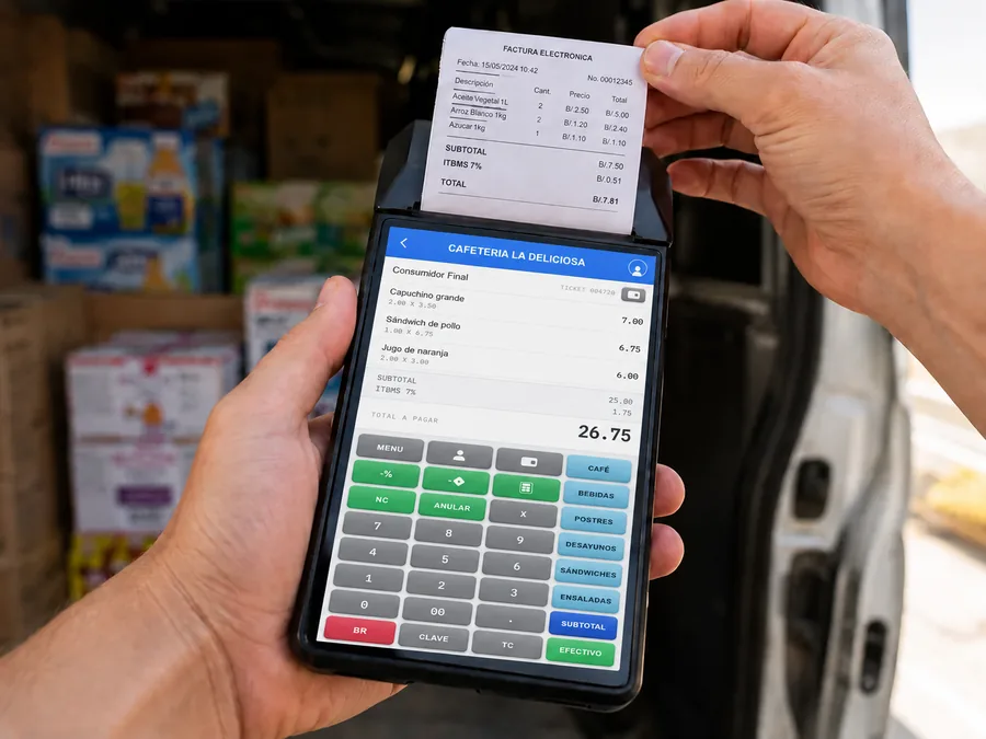 Terminal FácilPos de mano de 6 pulgadas sostenida con una mano frente a una van de reparto, con la venta abierta en pantalla y el ticket saliendo de la impresora integrada
